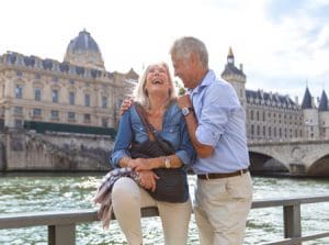 senior couple standing in front of a scenic canal laughing and holding each other