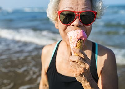senior woman enjoying a strawberry ice-cream cone on the beach