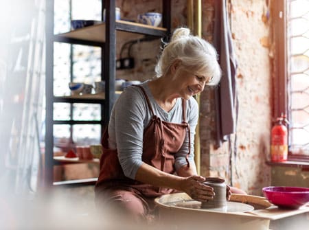 senior woman shaping clay on a pottery wheel