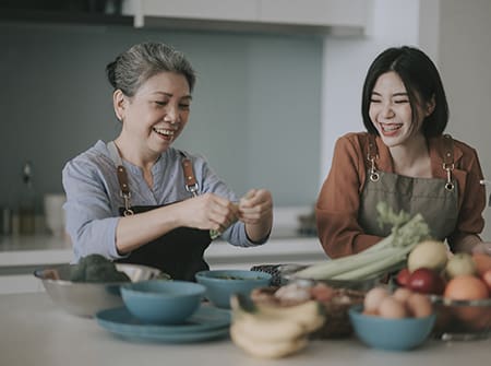 woman and her mother getting ready cooking meals for family at kitchen counter