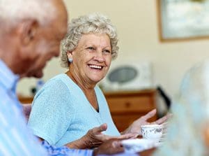 Happy senior woman spending leisure time with friends in nursing home