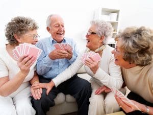 Happy senior men and women playing cards