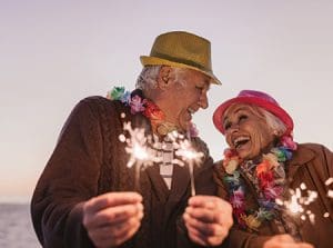 Laughing seniors celebrating New Year's with sparklers at the beach