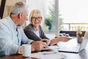 Senior couple doing home finances using laptop indoors