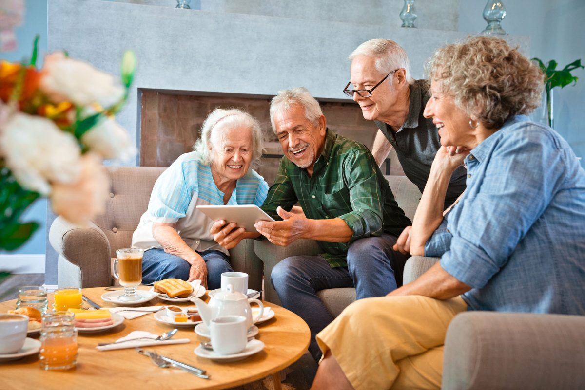 Smiling senior friends sharing digital tablet