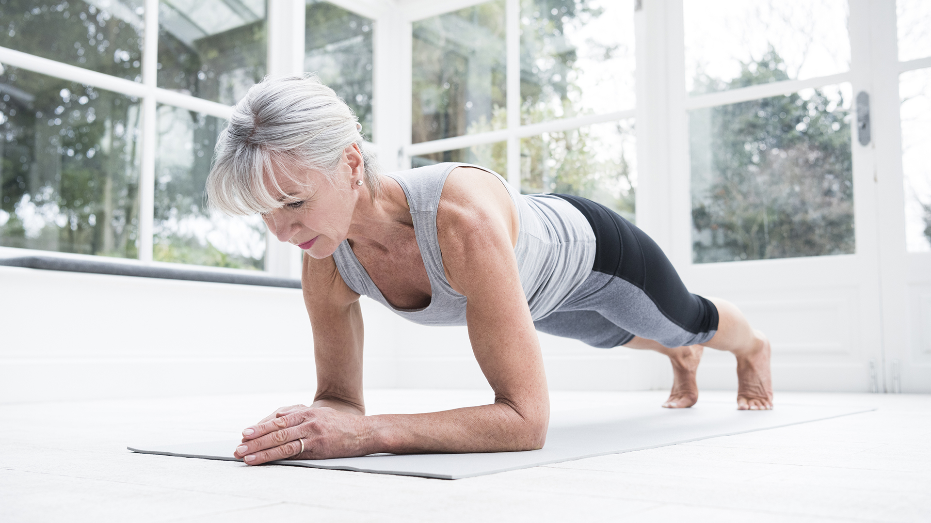 Senior woman in plank position in conservatory