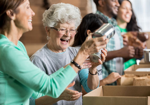 senior woman helping box canned foods for charity