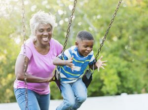 Senior woman with her young grandson on a swing set