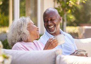 Senior Retired Couple Sitting Outdoors At Home Having Morning Coffee Together