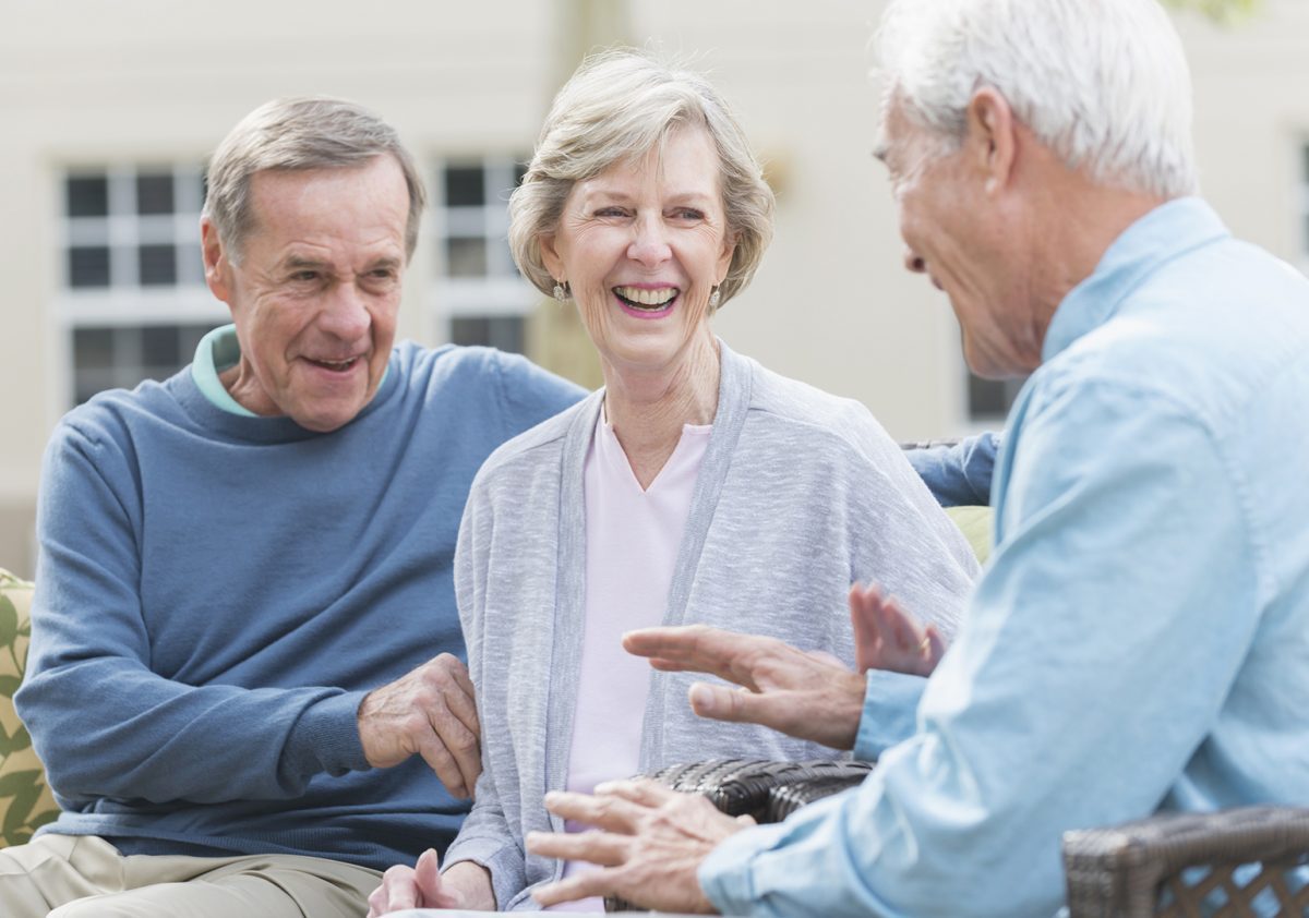 Group of seniors sitting outdoors, talking and laughing