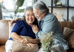 old senior retired couple enjoy talking conversation together on sofa with happiness laugh smile and joyful at home