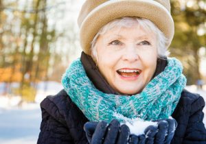 Happy senior woman smiling preparing snowball