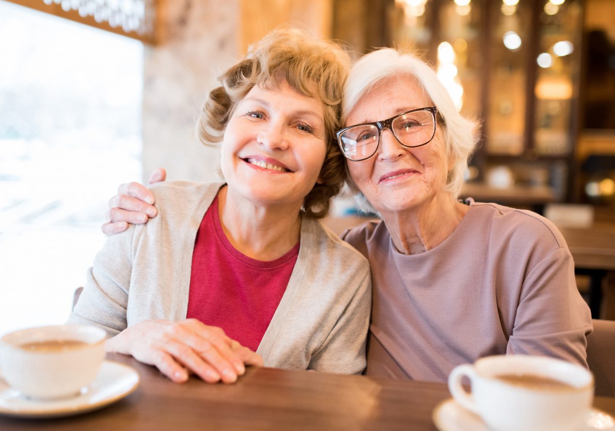 Cheerful senior lady friends in coffee shop