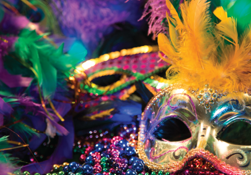 mardi gras inspired mask and beads on a purple table