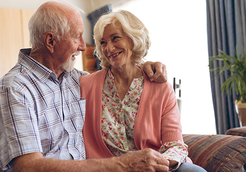senior couple sitting on sofa in their senior living apartment