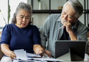 Serious couple worried about bills discuss unpaid bank debt paper, sad poor retired family looking at tablet counting loan payment worry about money problem