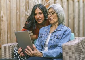 Senior woman learning to use tablet computer with the help of her adult daughter