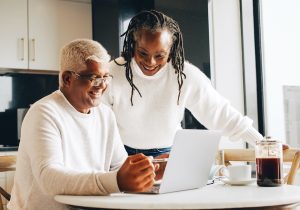 senior couple smiling happily while looking at a laptop screen