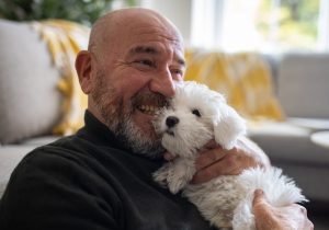 man embracing his Maltese dog puppy