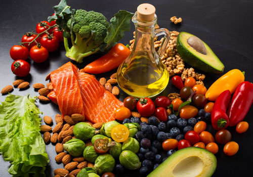assortment of salmon, nuts, fruits, vegetables, and a bottle of olive oil