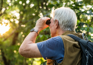 senior man outdoors birdwatching with binoculars