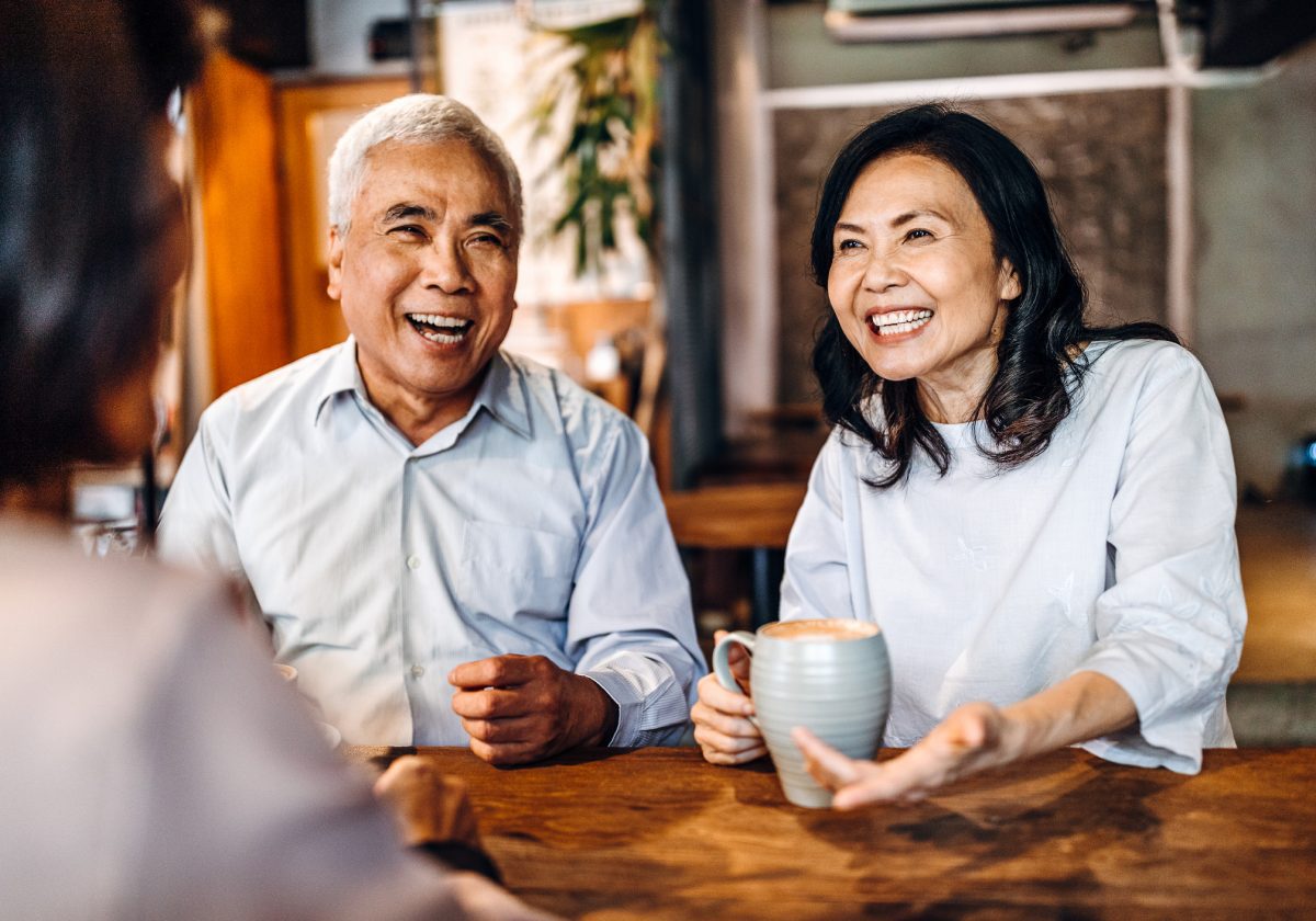 Group of three senior friends sitting and talking in cafe, laughing and having fun