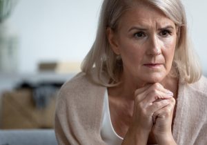 pensive senior woman sitting alone, thinking, feeling unwell