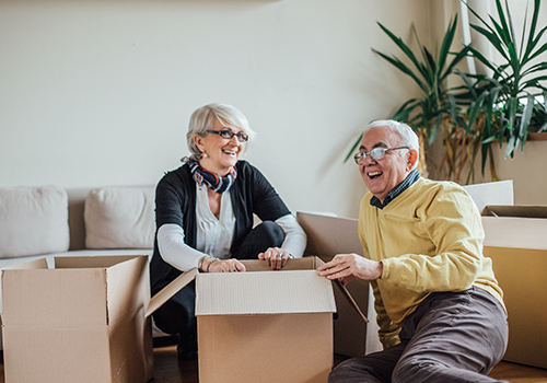 senior couple laughing together while packing up moving boxes in their home