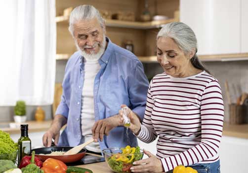 a senior couple preparing a salad in their kitchen