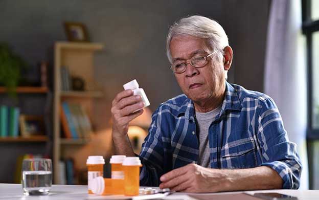 senior man looking at his medication at home

