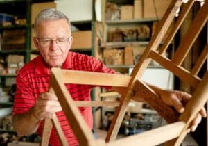 a senior man inspecting the wood chair he just built