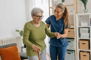caregiver helping a senior woman walk with a cane