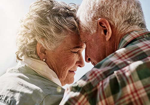 senior couple looking fondly at each other as they watch the sun set