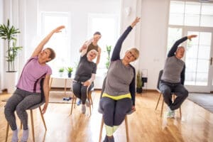 Active senior people practicing yoga during yoga class on chairs in yoga studio
