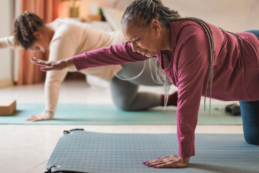 senior woman and daughter doing yoga exercise together at home