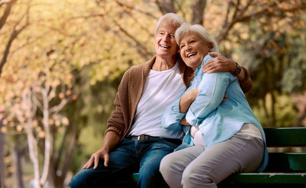 senior couple sitting outside on a park bench