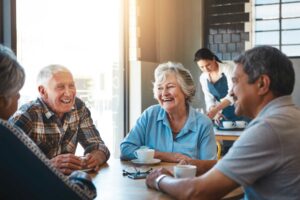 a group of senior friends sitting at a table chatting at a local coffee shop