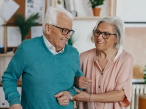 senior man walking with a cane and with the help of his wife