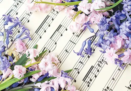 a sheet of music with lilacs and other flowers laying upon it
