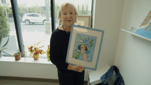 senior holding art in a studio